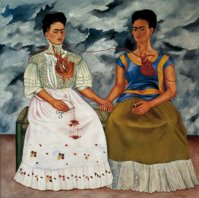 Pintura de duas mulheres sentadas, de mãos dadas, com corações expostos ligados por uma veia, simbolizando a dualidade emocional e cultural interior.